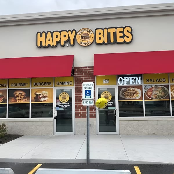 The exterior of Happy Bites restaurant with a red awning, large windows, and a reserved parking sign.