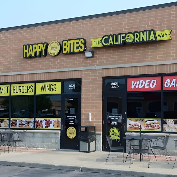 Exterior of Happy Bites restaurant with "The California Way" branding, outdoor seating, and menu signs.